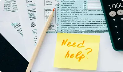 Tax documents, a calculator, and a sticky note with 'Need help?' written on it, symbolizing financial and tax assistance.