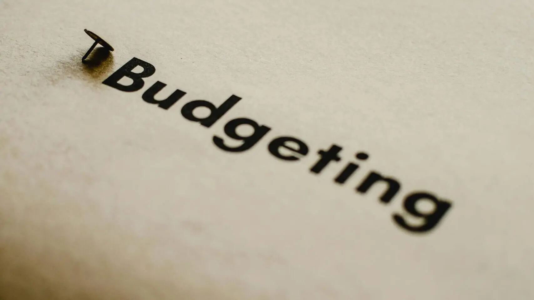 Close-up of the word 'Budgeting' printed on paper with a pushpin, symbolizing financial planning and management.