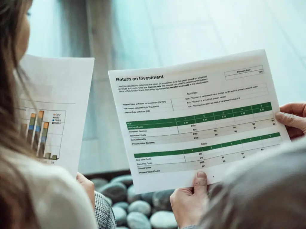 Financial consultants analyzing return on investment (ROI) reports with charts and data tables.